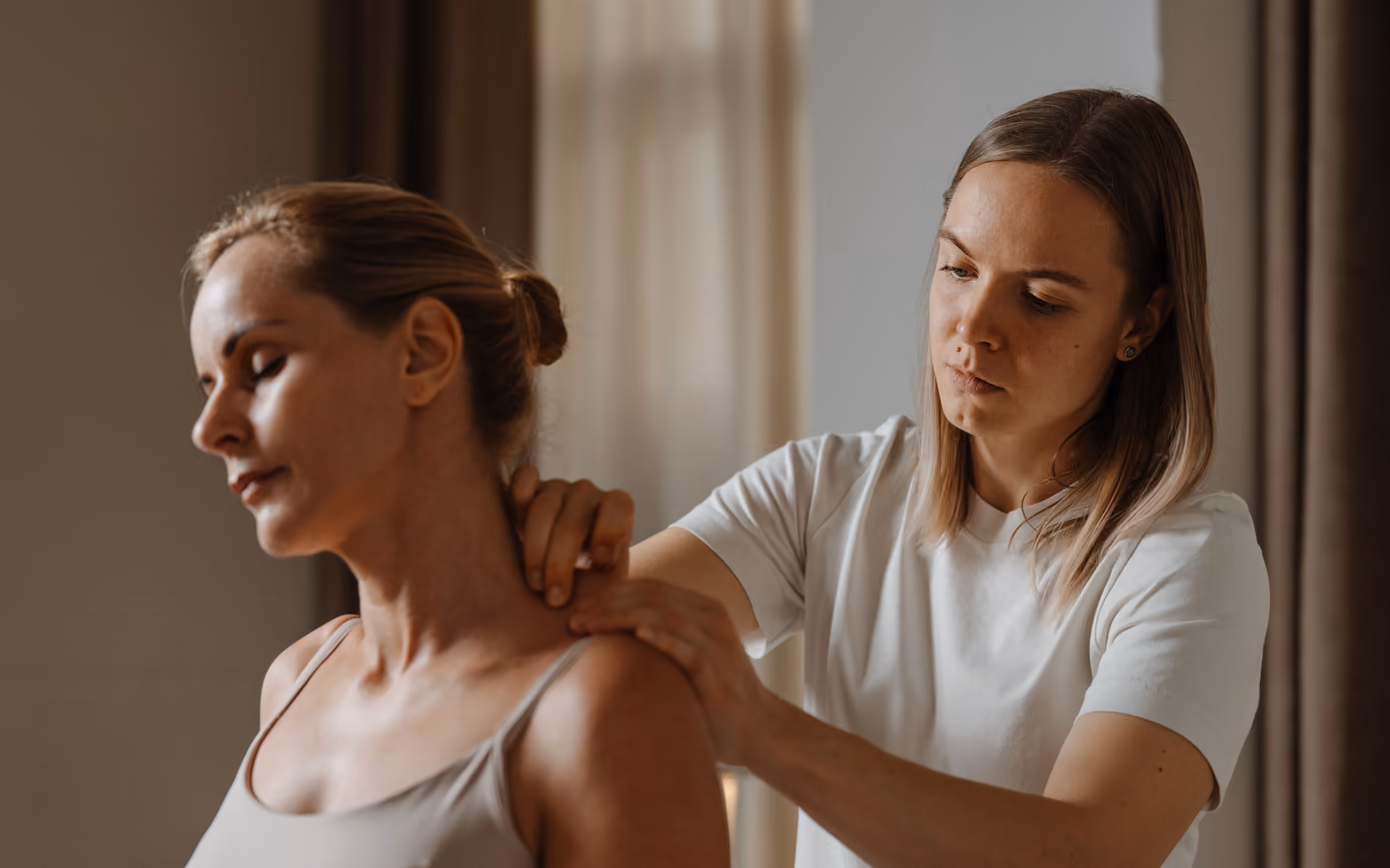 Therapist examining shoulders and neck while standing