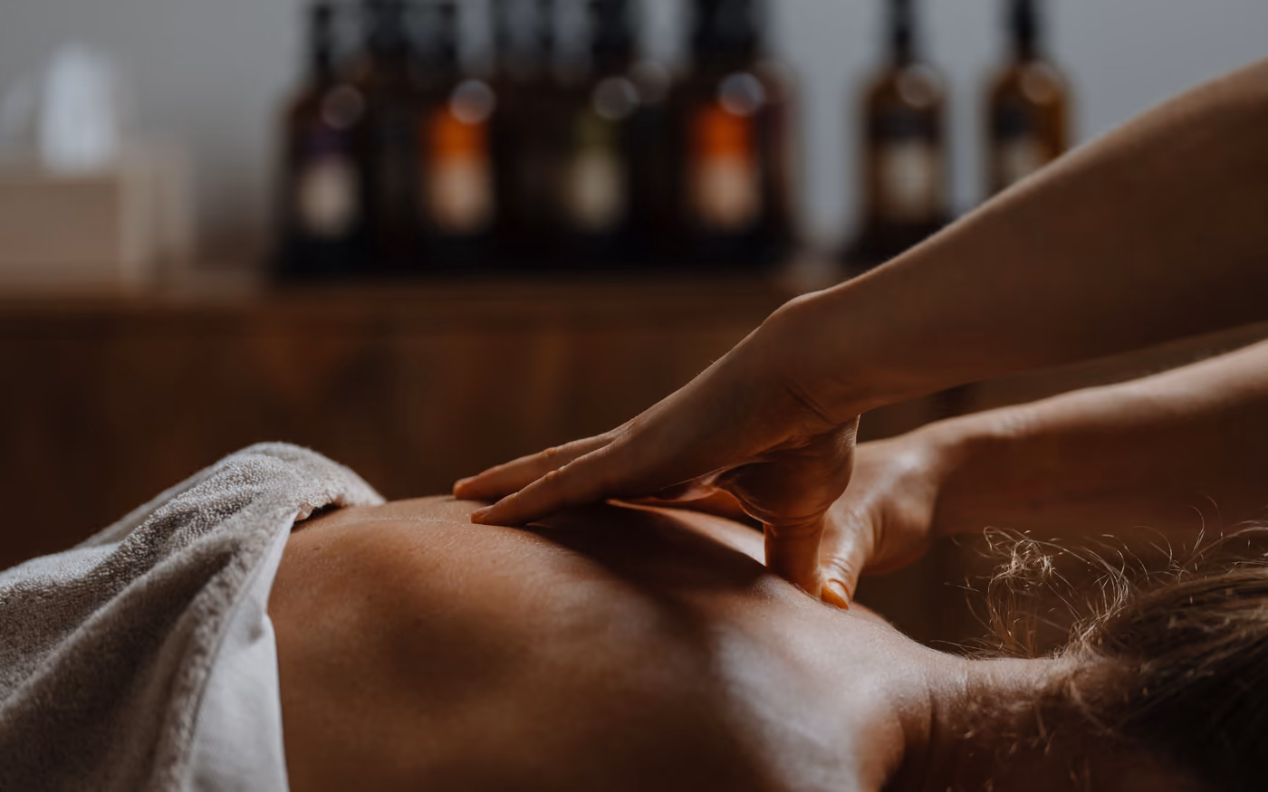 Hand on the lower back, oils in the background
